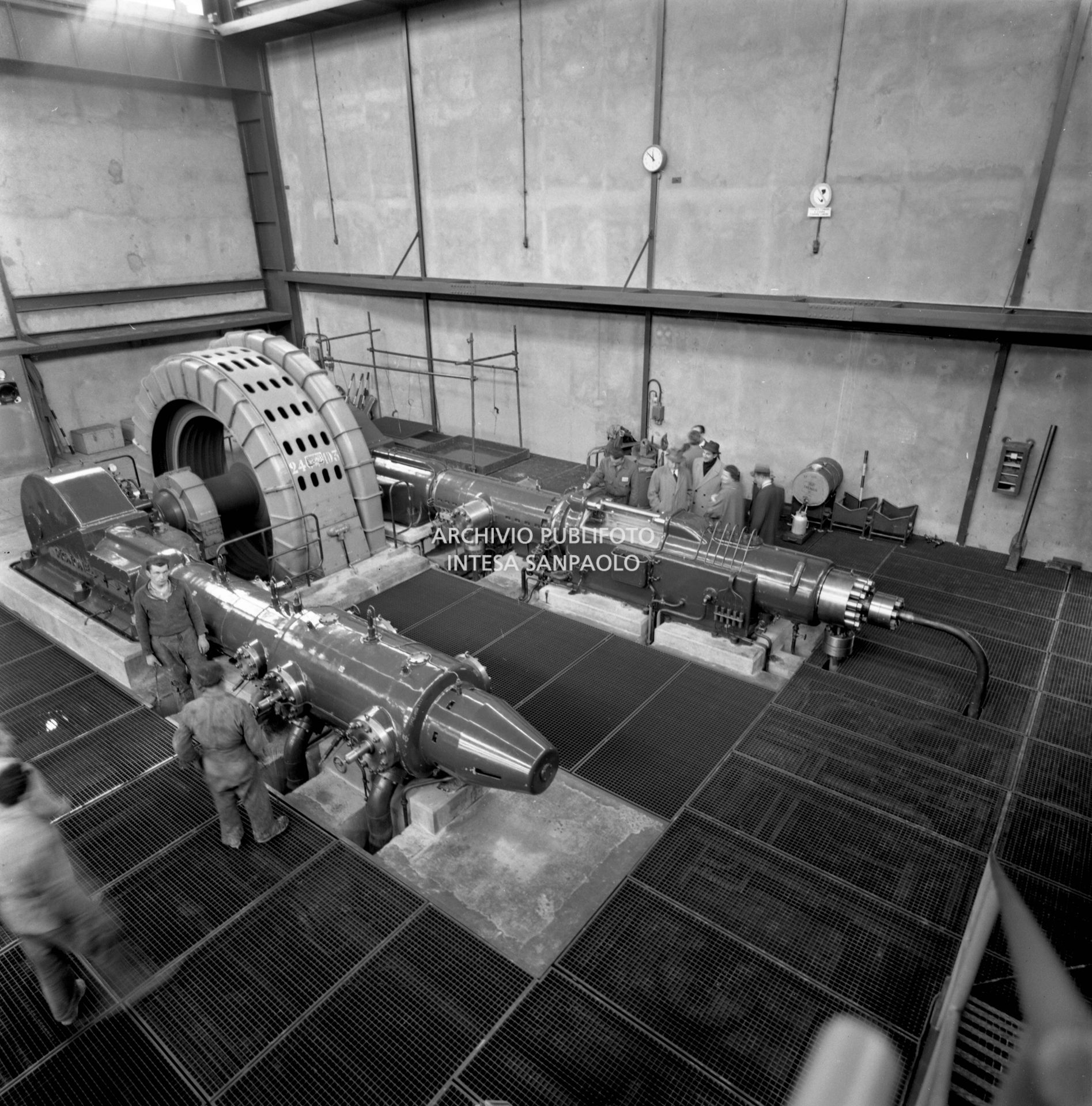 Interno dello stabilimento ripreso dall'alto: i visitatori osservano operai e macchinari al lavoro<br>441568