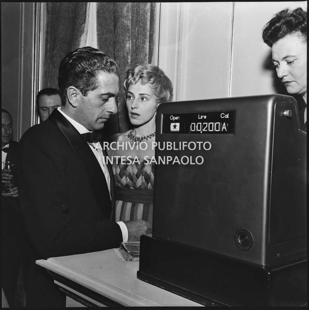 Emanuela di Castelbarco Toscanini ed il marito Luigi Filippo d'Acquarone alla cassa del bar del Teatro alla Scala in occasione della serata inaugurale della stagione lirica 1958-1959 con l'opera "Turandot", di Giacomo Puccini, diretta da Antonino Votto con la regia di Margherita Wallmann
