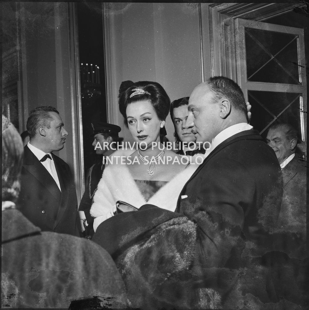 Lo stilista Pierre Balmain e Madeleine Kohler nel foyer del Teatro alla Scala in occasione della serata inaugurale della stagione lirica 1958-1959 con l'opera "Turandot", di Giacomo Puccini, diretta da Antonino Votto con la regia di Margherita Wallmann