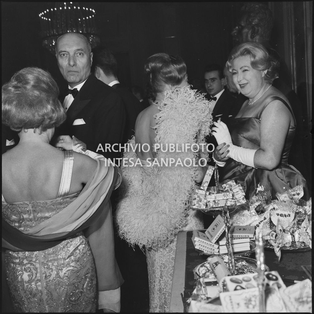 Alcuni spettatori nei pressi del banco dei dolci Perugina allestito al Teatro alla Scala in occasione della serata inaugurale della stagione lirica 1960-1961 con l'opera "Poliuto" di Gaetano Donizetti, diretta da Antonino Votto con la regia di Herbert Graf