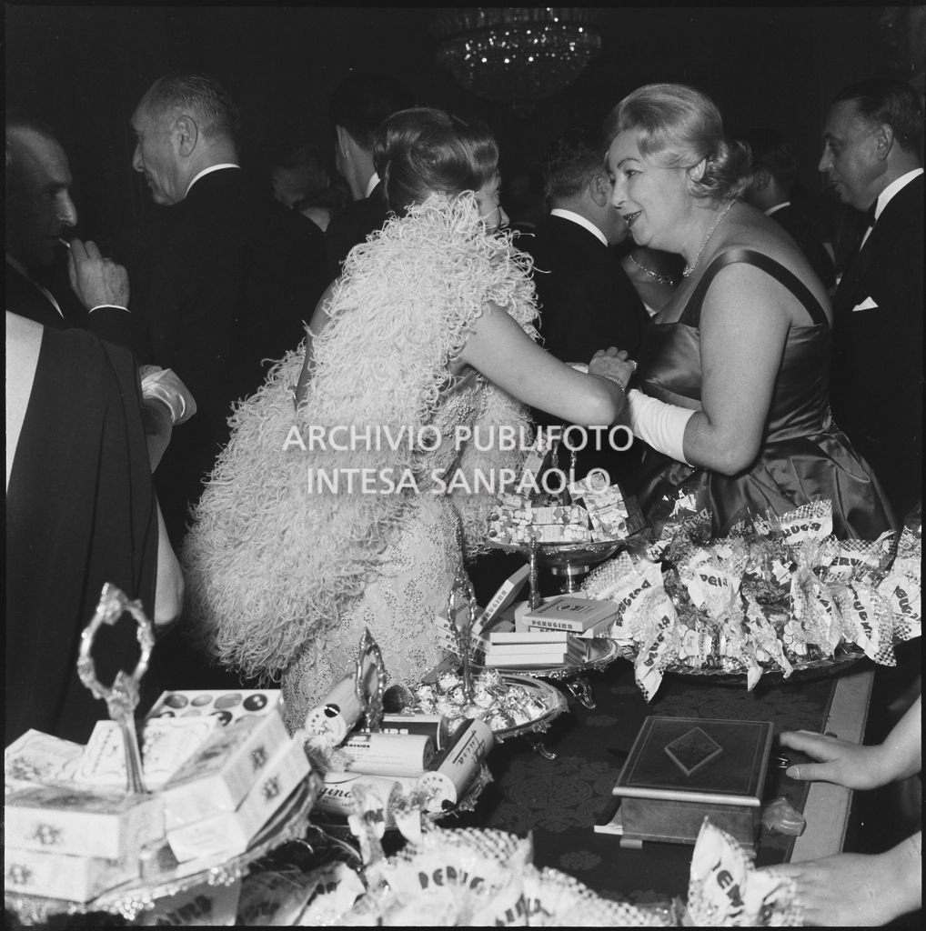 Alcuni spettatori nei pressi del banco dei dolci Perugina allestito al Teatro alla Scala in occasione della serata inaugurale della stagione lirica 1960-1961 con l'opera "Poliuto" di Gaetano Donizetti, diretta da Antonino Votto con la regia di Herbert Graf