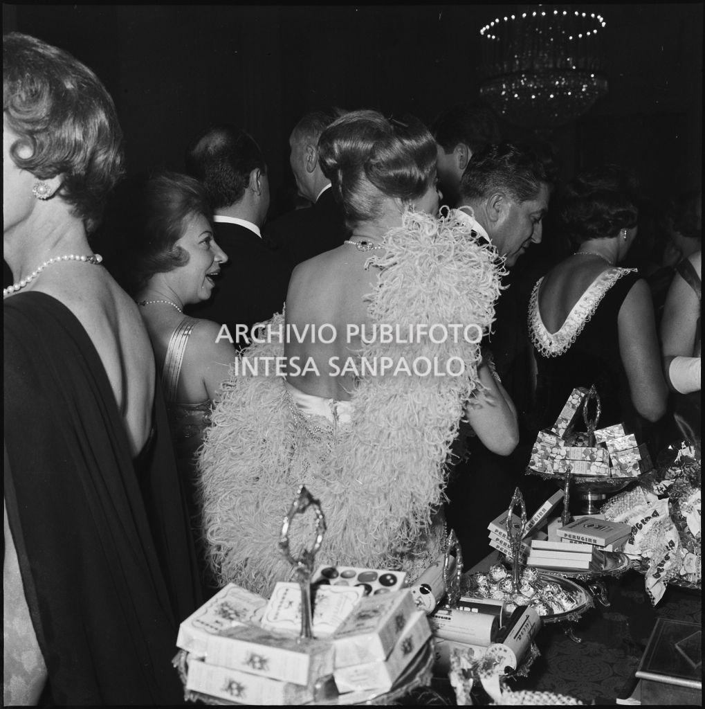 Alcuni spettatori nei pressi del banco dei dolci Perugina allestito al Teatro alla Scala in occasione della serata inaugurale della stagione lirica 1960-1961 con l'opera "Poliuto" di Gaetano Donizetti, diretta da Antonino Votto con la regia di Herbert Graf