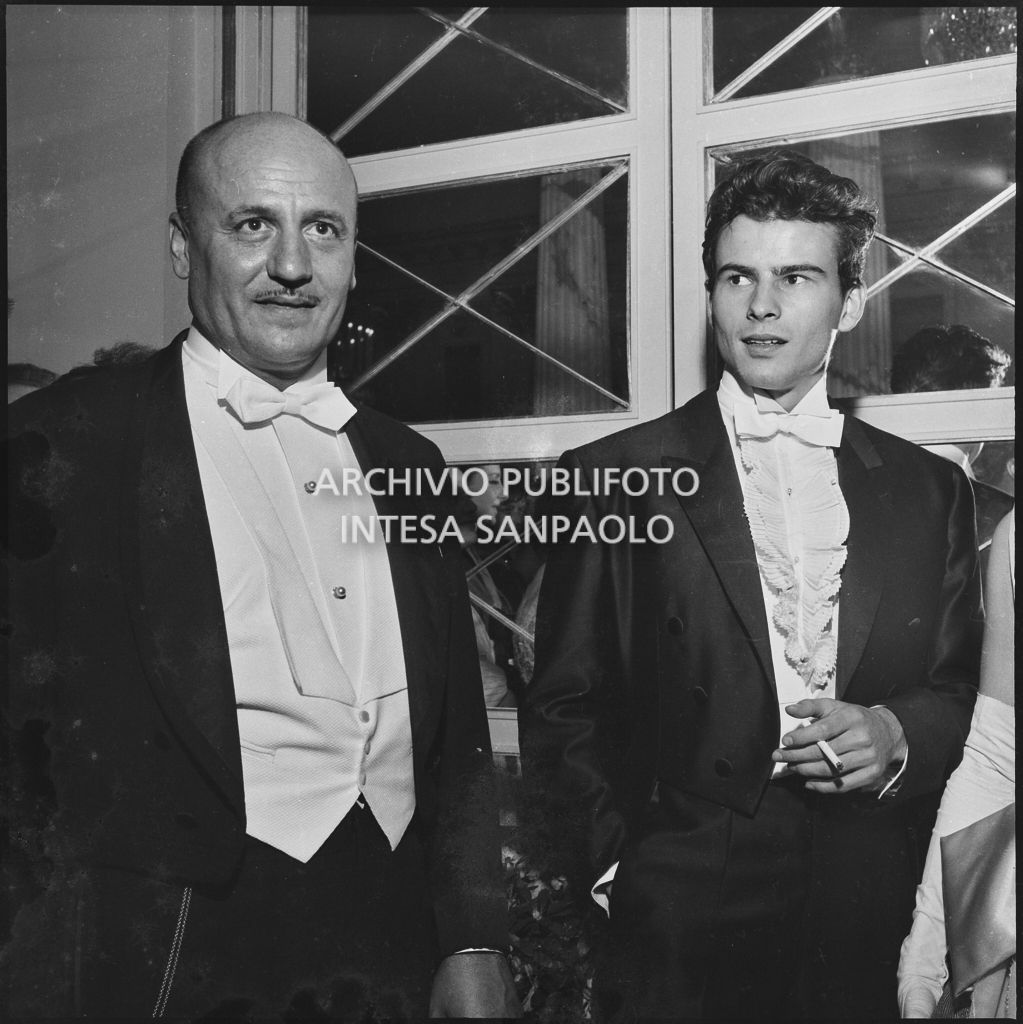 Lo stilista Pierre Balmain e l'attore Horst Buchholz nel foyer del Teatro alla Scala in occasione della serata inaugurale della stagione lirica 1960-1961 con l'opera "Poliuto" di Gaetano Donizetti, diretta da Antonino Votto con la regia di Herbert Graf