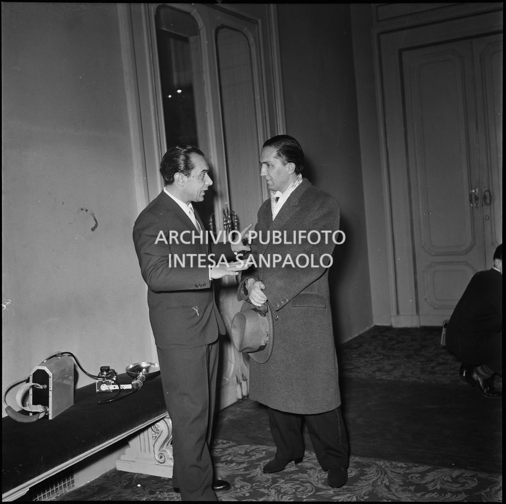 Un fotografo conversa con uno spettatore al Teatro alla Scala in occasione della serata inaugurale della stagione lirica 1951-1952 con l'opera "I vespri siciliani" di Giuseppe Verdi, diretta da Victor de Sabata, con la regia di Herbert Graf