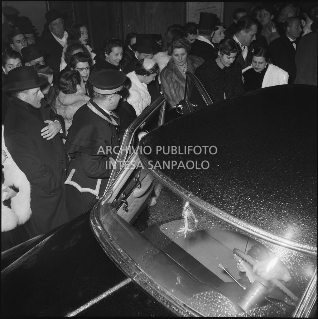 Un'automobile tra gli spettatori affollati all'esterno del Teatro alla Scala, nella galleria delle carrozze, la sera dell'inaugurazione della stagione lirica 1952-1953 con l'opera "Macbeth", di Giuseppe Verdi, diretta da Victor de Sabata, con la regia di Carl Ebert