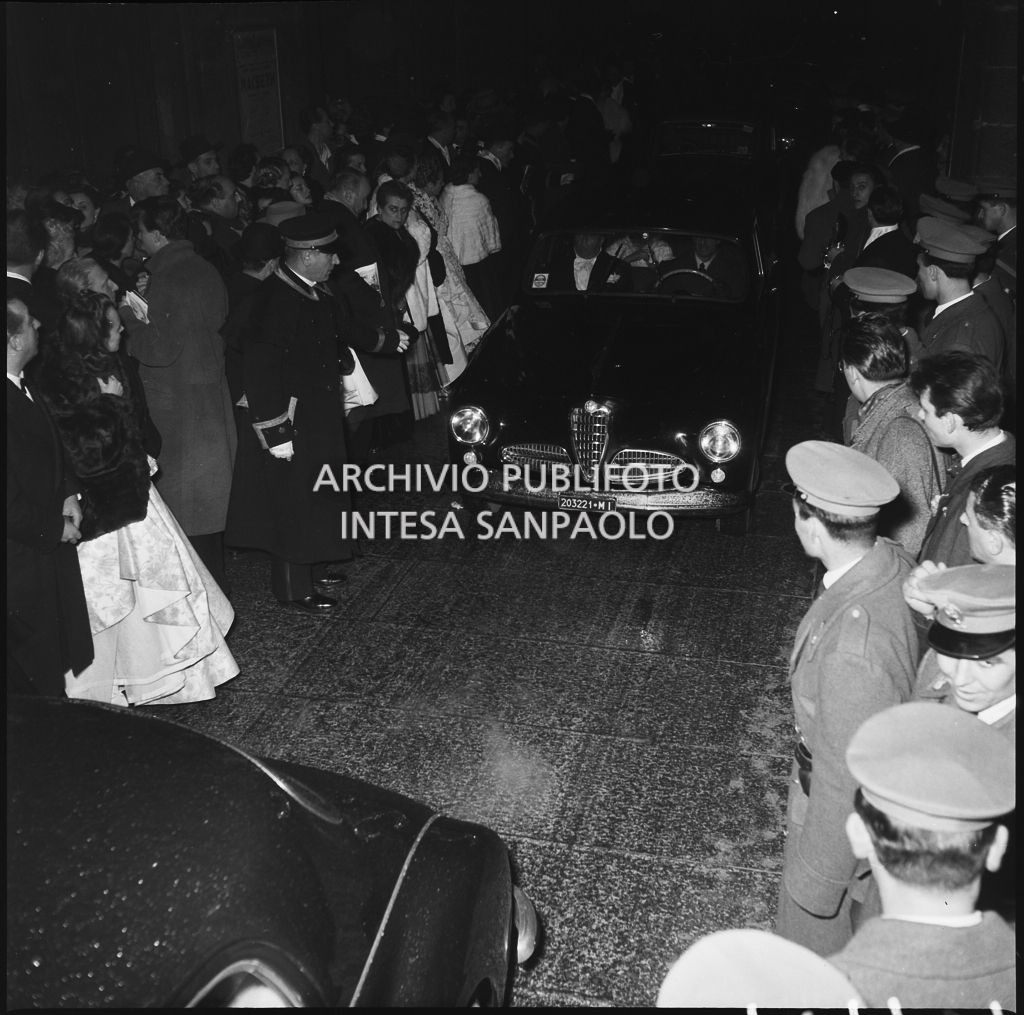 Un'automobile tra gli spettatori affollati all'esterno del Teatro alla Scala, nella galleria delle carrozze, la sera dell'inaugurazione della stagione lirica 1952-1953 con l'opera "Macbeth", di Giuseppe Verdi, diretta da Victor de Sabata, con la regia di Carl Ebert