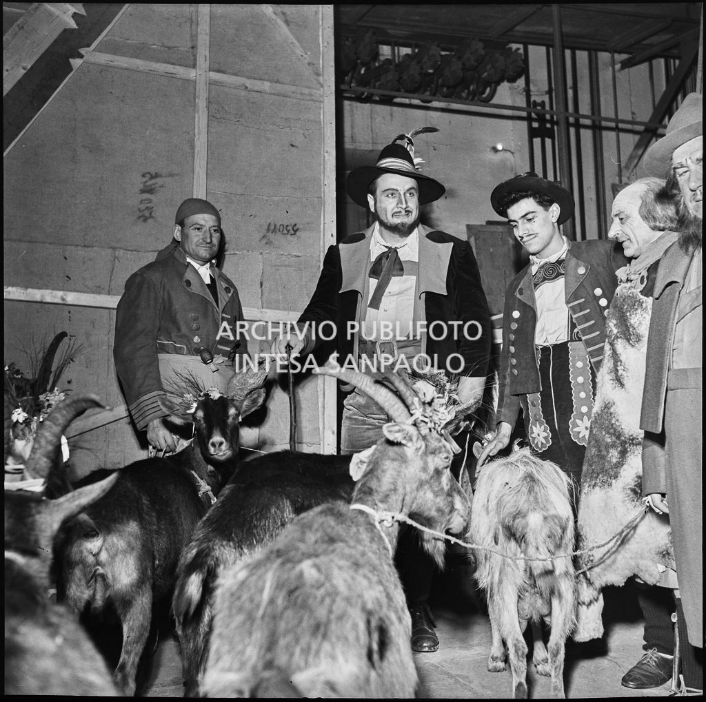 Il baritono Giangiacomo Guelfi (al centro) con attori e capre dietro le quinte al Teatro alla Scala la sera dell'inaugurazione della stagione lirica 1953-1954 con l'opera "La Wally", di Alfredo Catalani, diretta da Carlo Maria Giulini, con la regia di Tatiana Pavlova