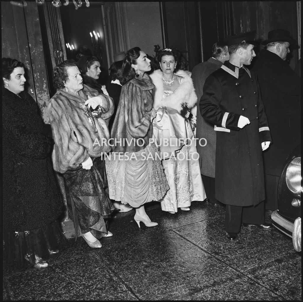 La signora Rizzoli ed altri spettatori nella galleria delle carrozze del Teatro alla Scala in attesa dell'automobile al termine della serata inaugurale della stagione lirica 1953-1954 con l'opera "La Wally", di Alfredo Catalani, diretta da Carlo Maria Giulini, con la regia di Tatiana Pavlova