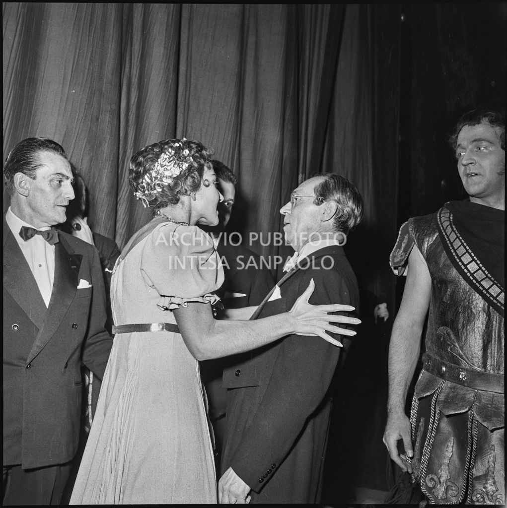 La soprano Maria Callas, in abiti di scena, discute con il direttore d'orchestra Antonino Votto al termine della rappresentazione dell'opera "La Vestale" che inaugura la stagione lirica 1954-1955 del Teatro alla Scala