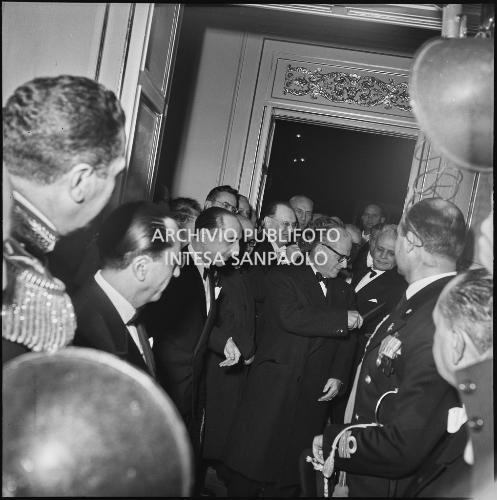 Il presidente della Repubblica Giovanni Gronchi tra la folla e i fotografi in occasione della serata inaugurale della stagione lirica 1955-1956 con l'opera "Norma" di Vincenzo Bellini, diretta da Antonino Votto, con la regia di Margherita Wallmann