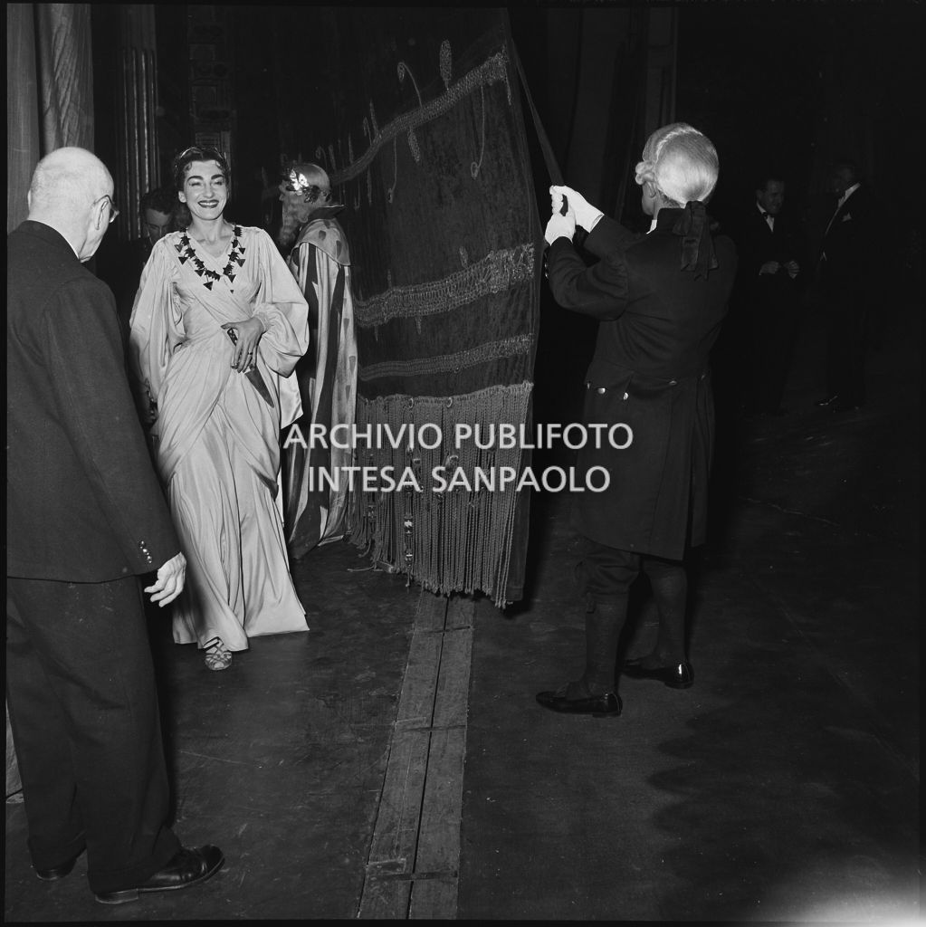 La soprano Maria Callas dietro il sipario del Teatro alla Scala al termine della rappresentazione dell'opera "Norma" di Vincenzo Bellini, diretta da Antonino Votto, con la regia di Margherita Wallmann, che inaugura la stagione lirica 1955-1956