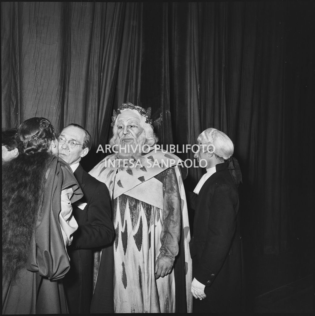 Il direttore d'orchestra Antonino Votto bacia la soprano Maria Callas dietro le quinte del Teatro alla Scala, alle loro spalle il basso Nicola Zaccaria, al termine della rappresentazione dell'opera "Norma" di Vincenzo Bellini, diretta da Antonino Votto, con la regia di Margherita Wallmann, che inaugura la stagione lirica 1955-1956