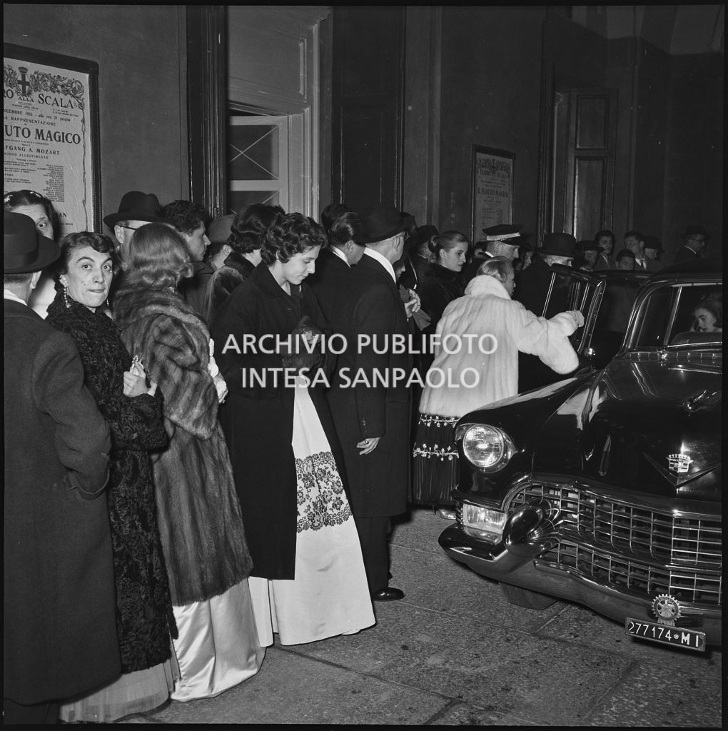 Spettatori in attesa delle automobili nella galleria delle carrozze del Teatro alla Scala al termine della serata inaugurale della stagione lirica 1955-1956 con l'opera "Norma" di Vincenzo Bellini, diretta da Antonino Votto, con la regia di Margherita Wallmann