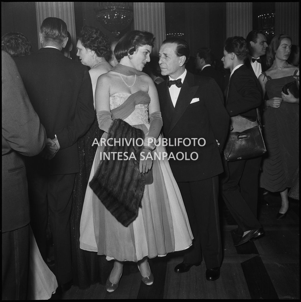 Due spettatori nel foyer del Teatro alla Scala, gremito di gente, in occasione della serata inaugurale della stagione lirica 1956-1957 con l'opera "Aida" di Giuseppe Verdi, diretta da Antonino Votto, con la regia di Franco Enriquez