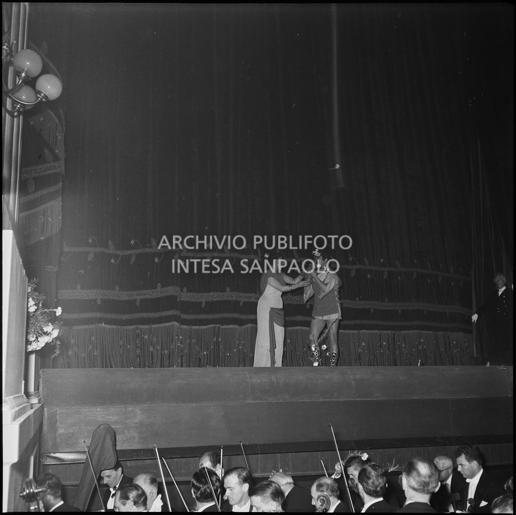 Il soprano Antonietta Stella e il tenore Giuseppe Di Stefano, sul palco del Teatro alla Scala, ricevono fiori dal pubblico in occasione dell'inaugurazione della stagione lirica 1956-1957 con l'opera "Aida" di Giuseppe Verdi, diretta da Antonino Votto, con la regia di Franco Enriquez