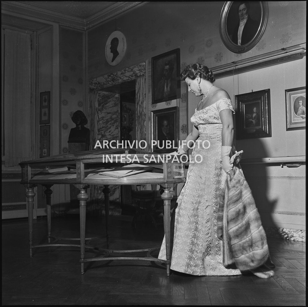 Una spettatrice osserva una teca del Teatro alla Scala in occasione della serata inaugurale della stagione lirica 1956-1957 con l'opera "Aida" di Giuseppe Verdi, diretta da Antonino Votto, con la regia di Franco Enriquez