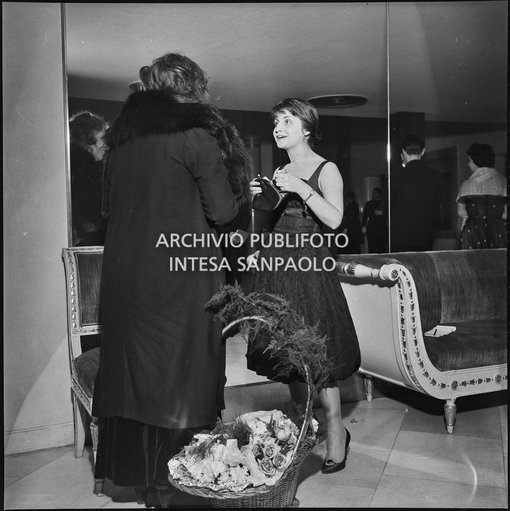 Una spettatrice acquista un mazzo di fiori nel foyer della Piccola Scala in occasione della serata inaugurale della stagione lirica 1956-1957 con l'opera "La cecchina ossia la buona figliola" di Niccolò Vito Piccinni, diretta da Nino Sanzogno, con la regia di Franco Zeffirelli