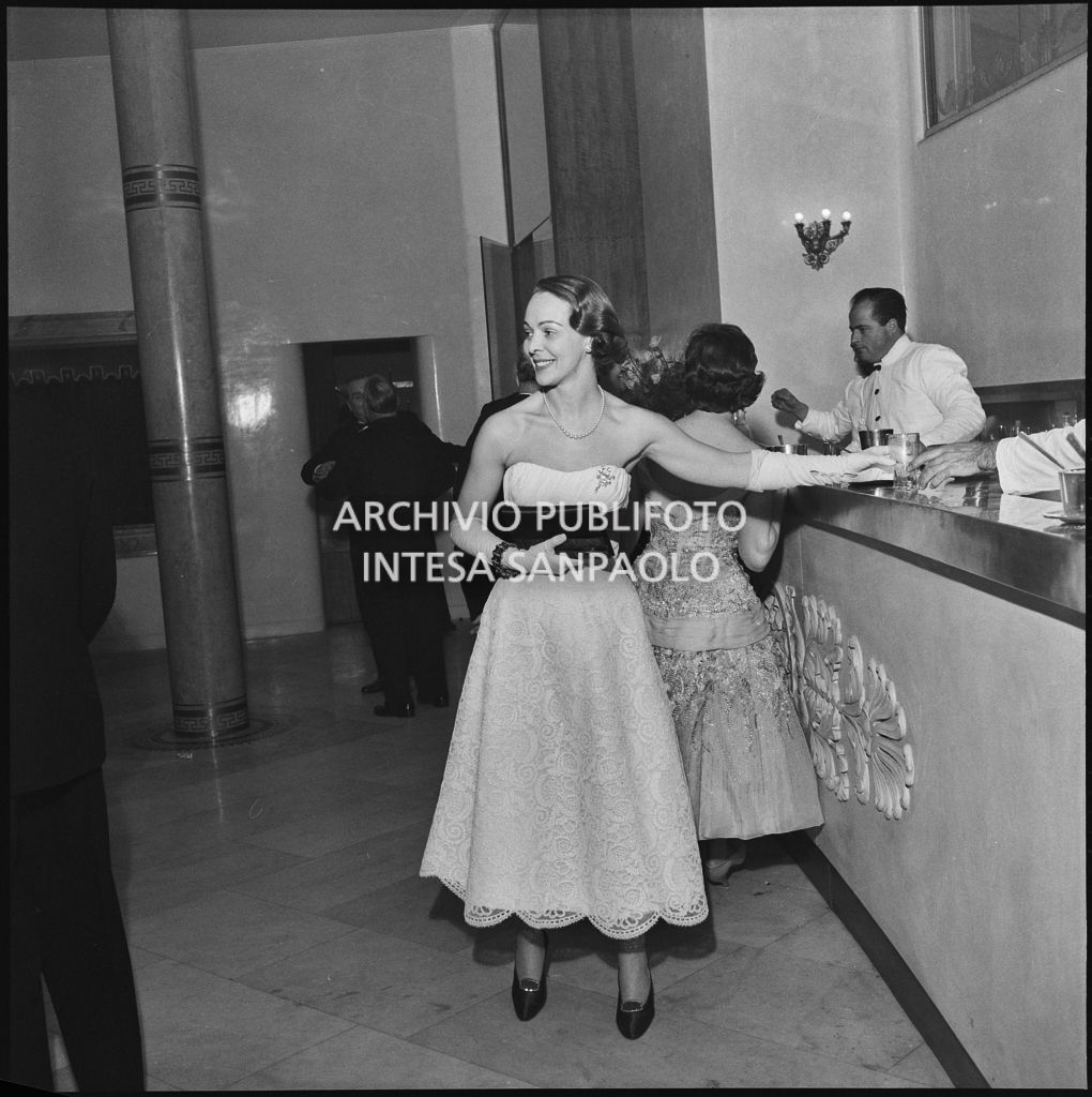Una spettatrice si serve al ber della Piccola Scala in occasione della serata inaugurale della stagione lirica 1956-1957 con l'opera "La cecchina ossia la buona figliola" di Niccolò Vito Piccinni, diretta da Nino Sanzogno, con la regia di Franco Zeffirelli