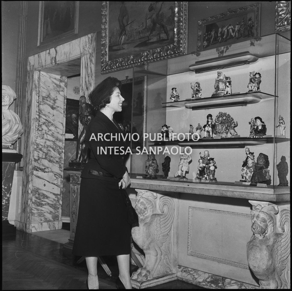 Il mezzosoprano Giulietta Simionato osserva una vetrina espositiva del museo del Teatro alla Scala in occasione della serata inaugurale della stagione lirica 1957-1958 con l'opera "Un ballo in maschera", di Giuseppe Verdi, diretta da Gianandrea Gavazzeni con la regia di Margherita Wallmann