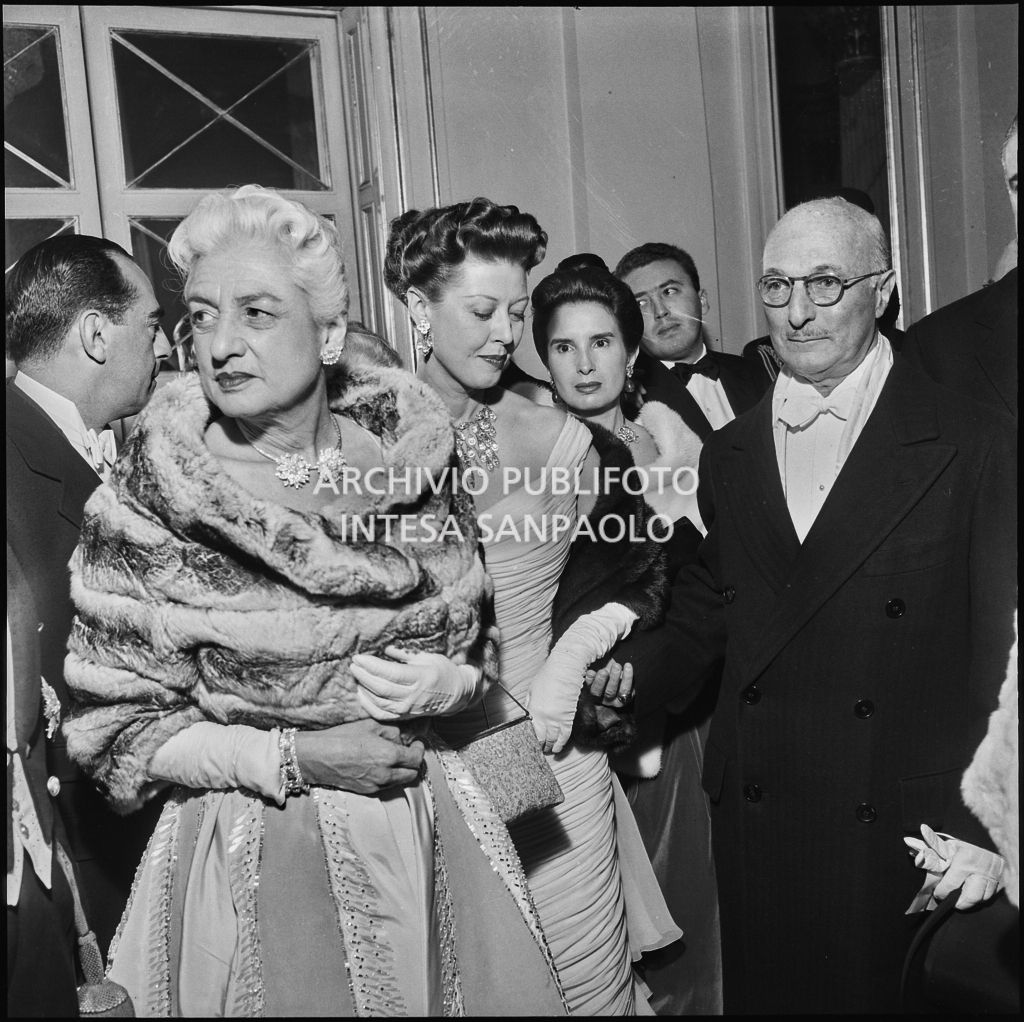 L'ambasciatore americano James David Zellerbach con la moglie, la figlia ed altri spettatori nel foyer del Teatro alla Scala in occasione della serata inaugurale della stagione lirica 1957-1958 con l'opera "Un ballo in maschera", di Giuseppe Verdi, diretta da Gianandrea Gavazzeni con la regia di Margherita Wallmann