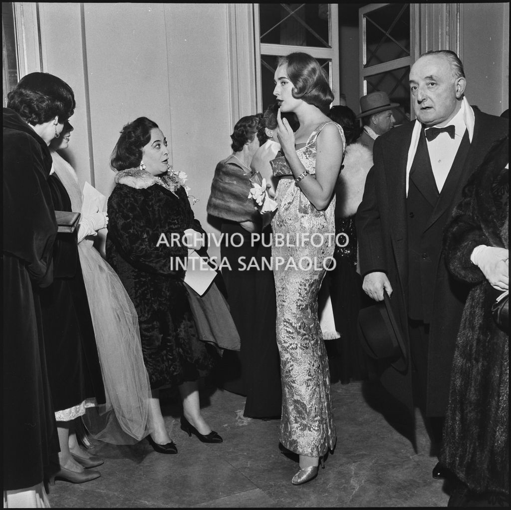 Beatrice Faccioli, Miss Italia 1957,  ed altri spettatori nel foyer del Teatro alla Scala in occasione della serata inaugurale della stagione lirica 1957-1958 con l'opera "Un ballo in maschera", di Giuseppe Verdi, diretta da Gianandrea Gavazzeni con la regia di Margherita Wallmann