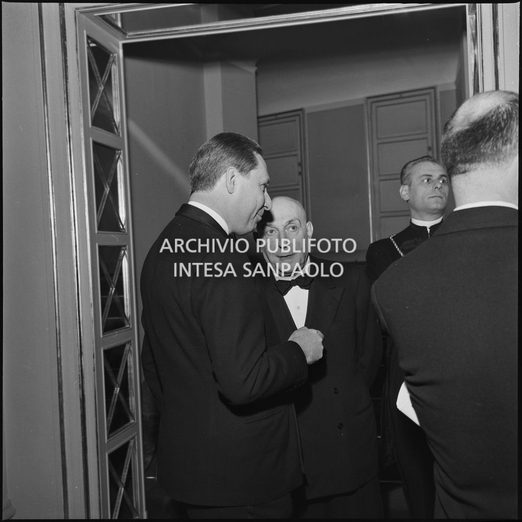 Due spettatori conversano nel foyer del Teatro alla Scala in occasione della serata inaugurale della stagione lirica 1958-1959, aperta con l'opera "Turandot", di Giacomo Puccini, diretta da Antonino Votto con la regia di Margherita Wallmann