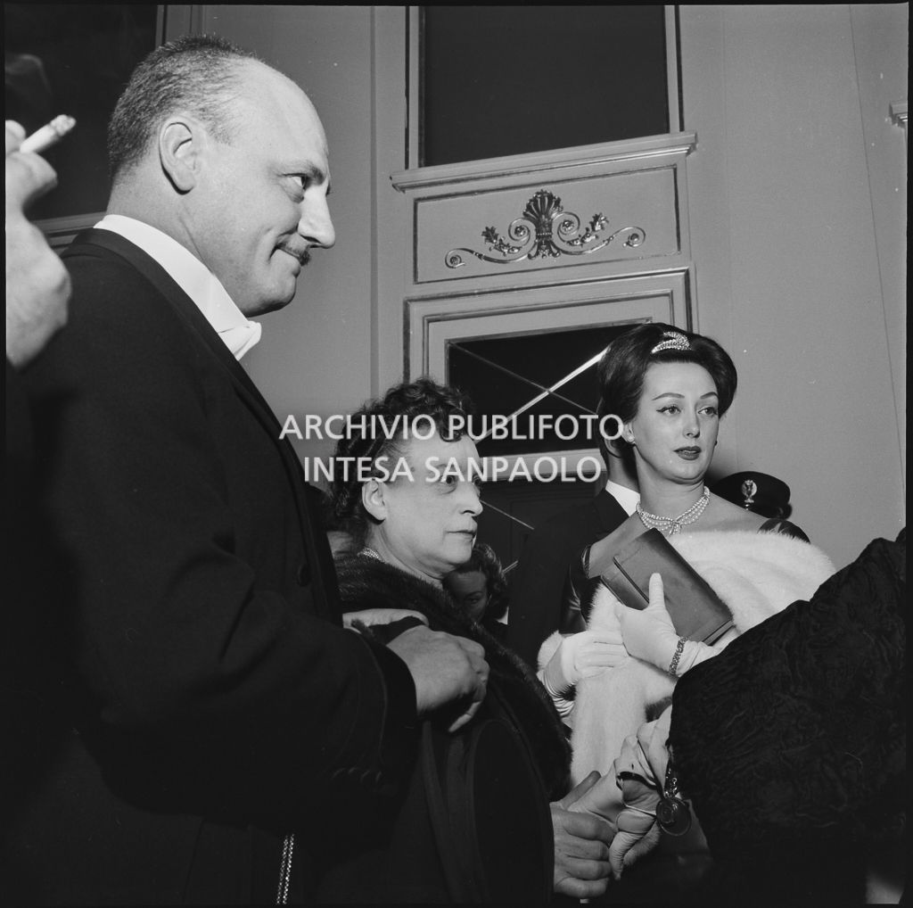 Lo stilista Pierre Balmain, Madeleine Kohler e un'altra spettatrice nel foyer del Teatro alla Scala in occasione della serata inaugurale della stagione lirica 1958-1959 con l'opera "Turandot", di Giacomo Puccini, diretta da Antonino Votto con la regia di Margherita Wallmann