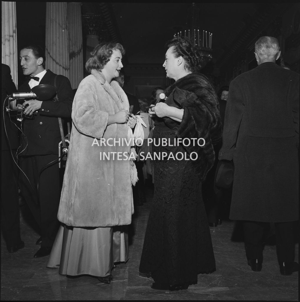 Due spettatrici discutono nel foyer del Teatro alla Scala in occasione della serata inaugurale della stagione lirica 1958-1959 con l'opera "Turandot", di Giacomo Puccini, diretta da Antonino Votto con la regia di Margherita Wallmann