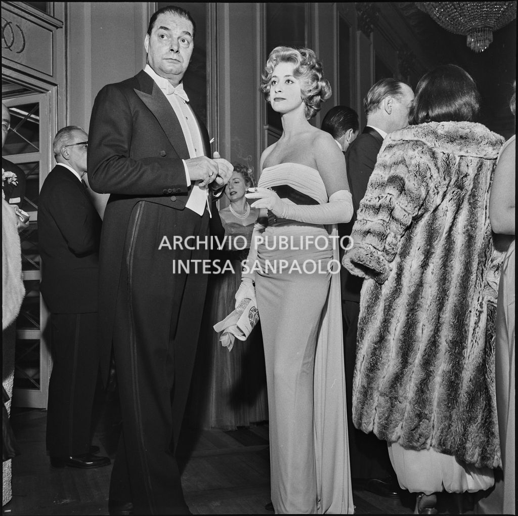 Sandra Marin in compagnia di un uomo nel foyer del Teatro alla Scala in occasione della serata inaugurale della stagione lirica 1958-1959 con l'opera "Turandot", di Giacomo Puccini, diretta da Antonino Votto con la regia di Margherita Wallmann