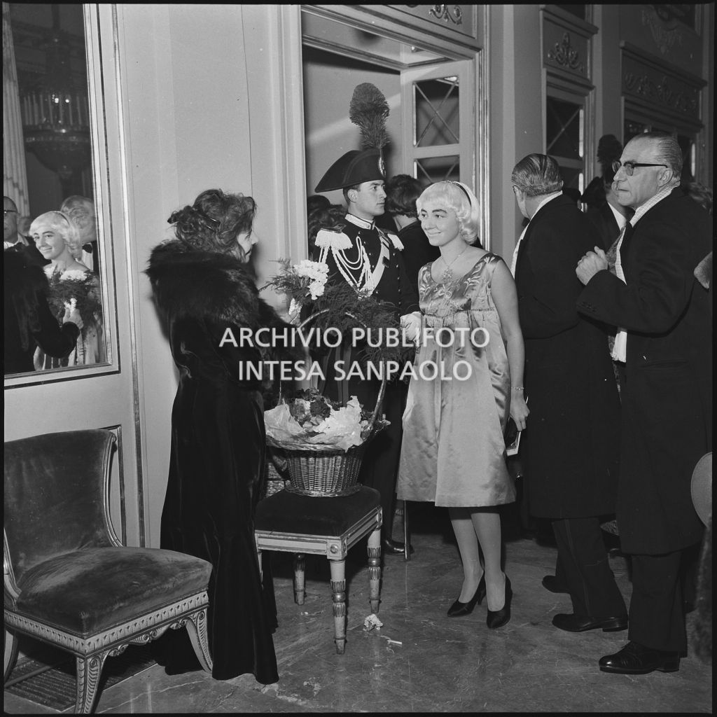 Una spettatrice riceve un mazzo di fiori nel foyer del Teatro alla Scala in occasione della serata inaugurale della stagione lirica 1958-1959 con l'opera "Turandot", di Giacomo Puccini, diretta da Antonino Votto con la regia di Margherita Wallmann
