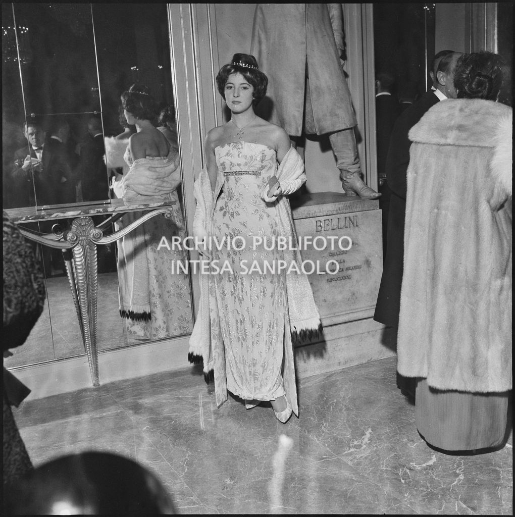 Una spettatrice, in posa davanti alla statua di Vincenzo Bellini, al Teatro alla Scala in occasione della serata inaugurale della stagione lirica 1958-1959 con l'opera "Turandot", di Giacomo Puccini, diretta da Antonino Votto con la regia di Margherita Wallmann