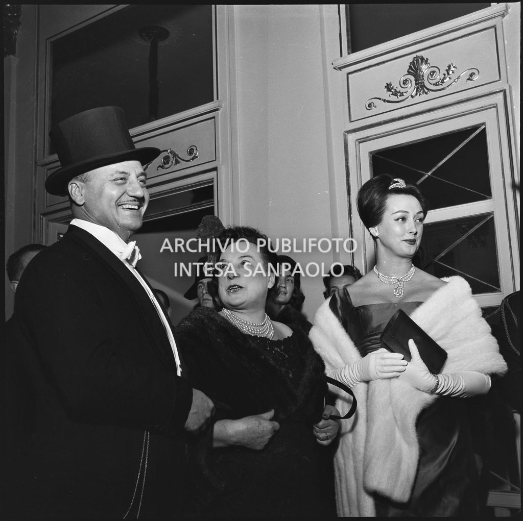 Lo stilista Pierre Balmain, Madeleine Kohler ed un'altra spettatrice nel foyer del Teatro alla Scala in occasione della serata inaugurale della stagione lirica 1958-1959 con l'opera "Turandot", di Giacomo Puccini, diretta da Antonino Votto con la regia di Margherita Wallmann
