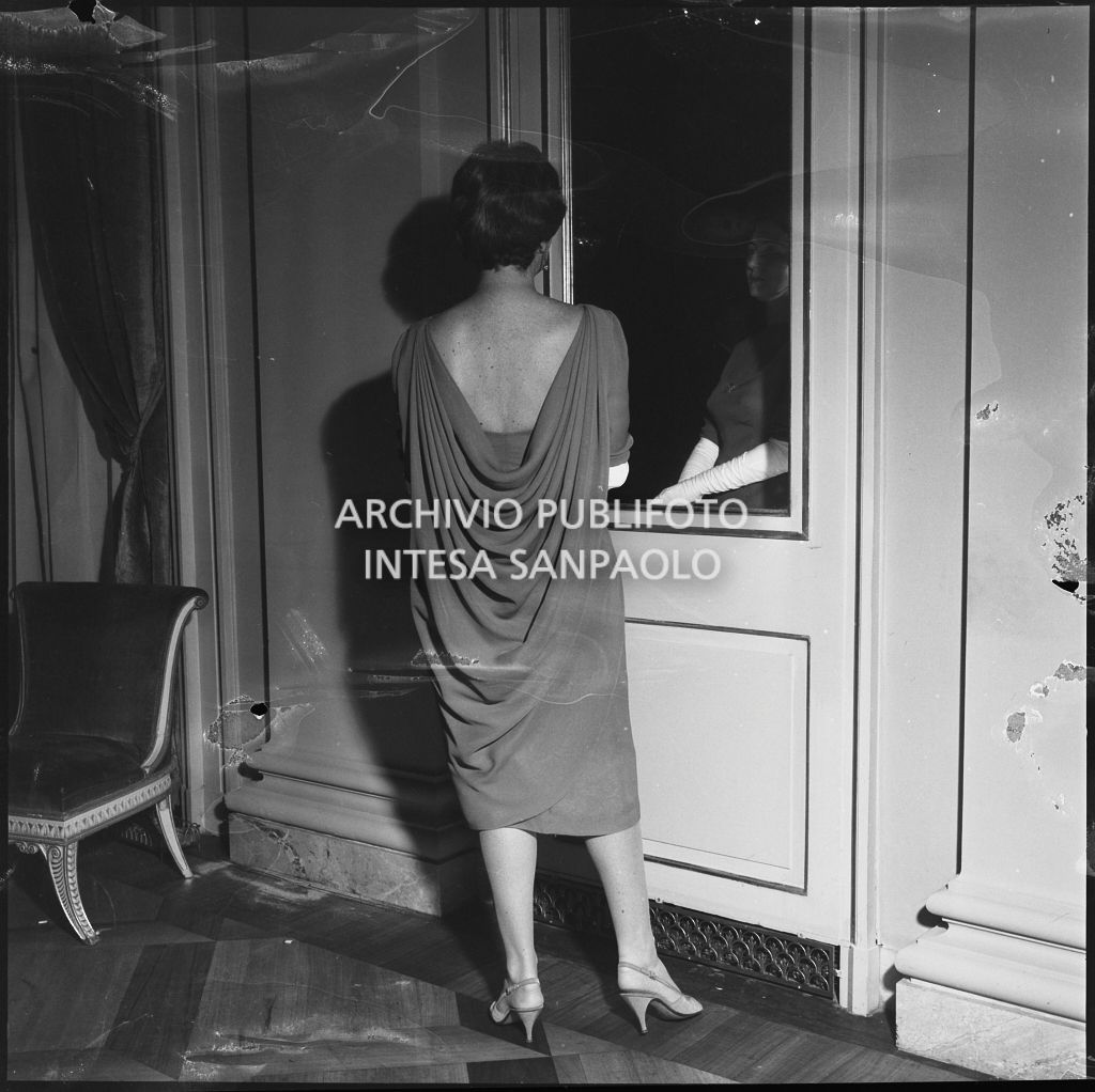 Una spettatrice davanti allo specchio nel foyer del Teatro alla Scala in occasione della serata inaugurale della stagione lirica 1958-1959 con l'opera "Turandot", di Giacomo Puccini, diretta da Antonino Votto con la regia di Margherita Wallmann