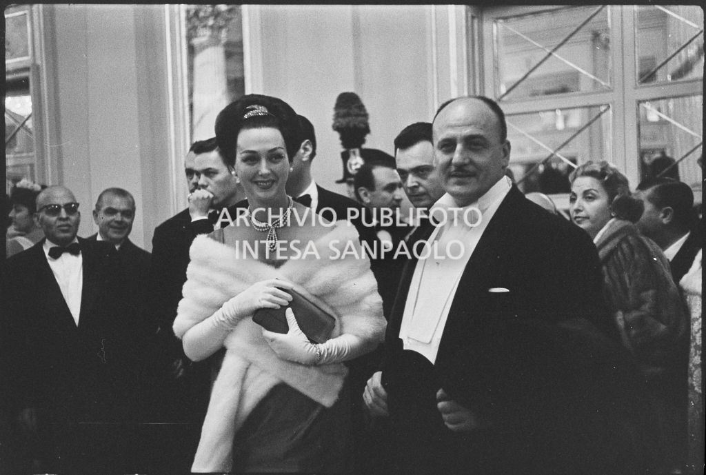 Lo stilista Pierre Balmain e Madeleine Kohler nel foyer del Teatro alla Scala in occasione della serata inaugurale della stagione lirica 1958-1959 con l'opera "Turandot", di Giacomo Puccini, diretta da Antonino Votto, con la regia di Margherita Wallmann