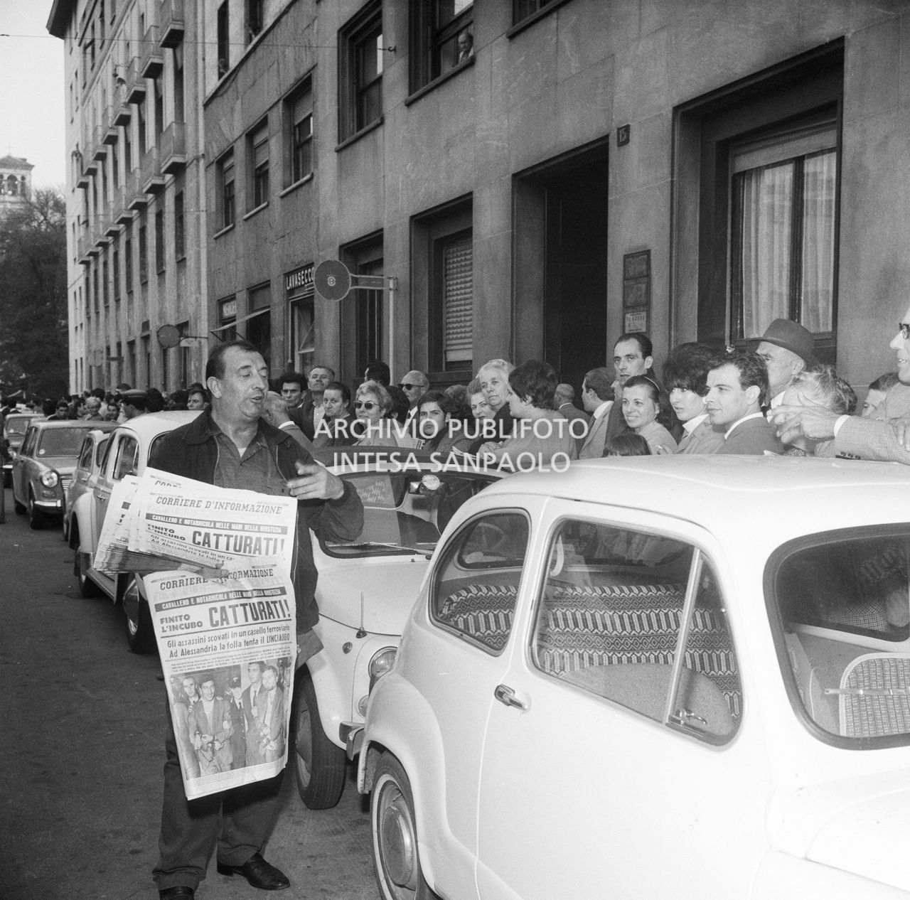 Uno strillone vende giornali alla gente in attesa davanti alla caserma di via della Moscova a Milano