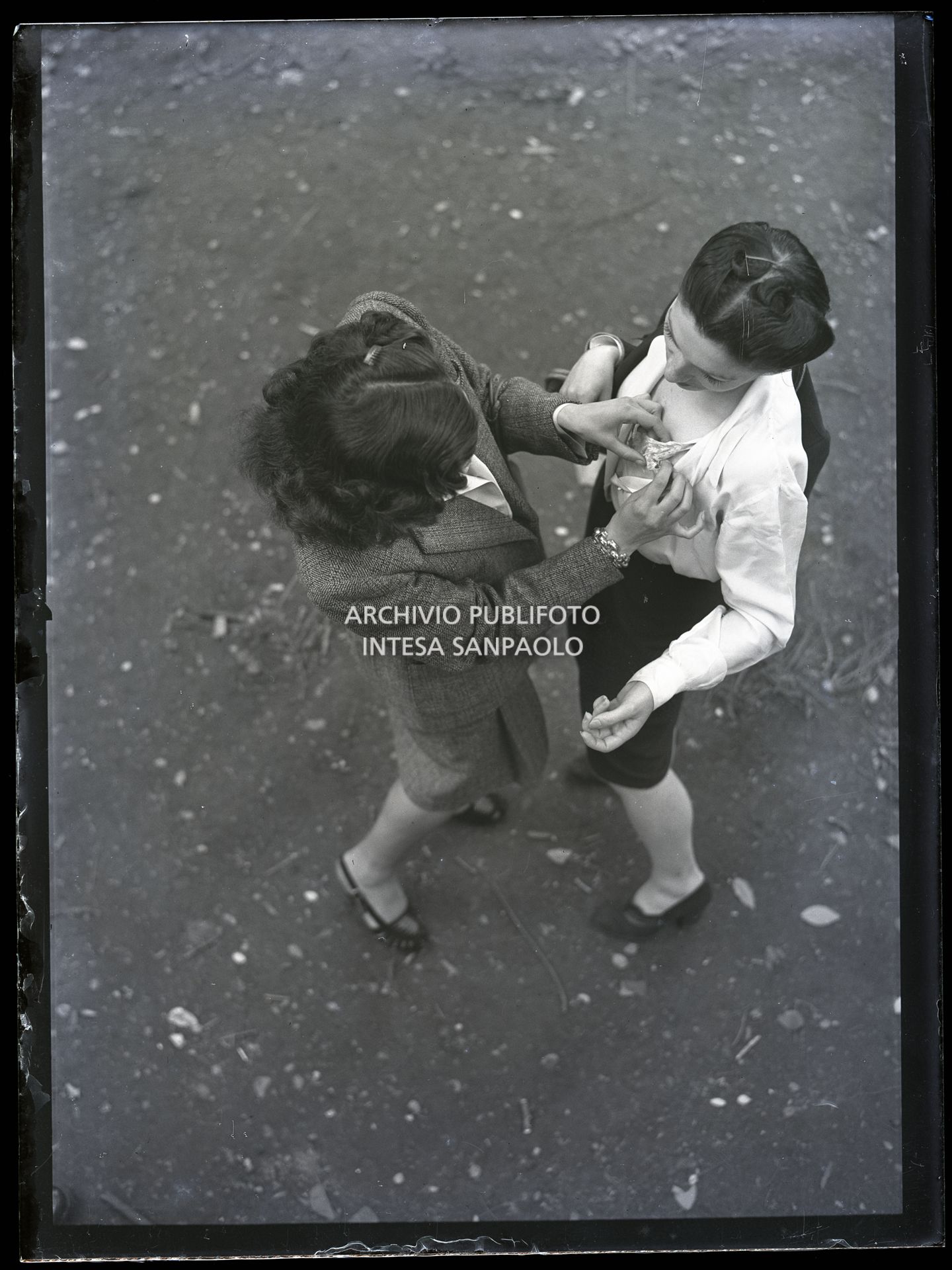 Una donna sistema la camicetta a un'altra per strada