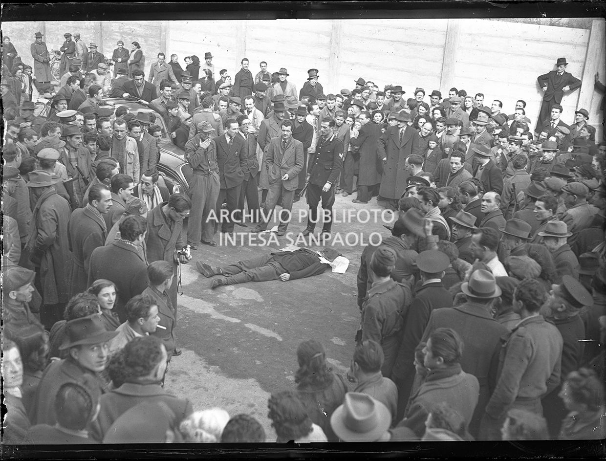 Folla di curiosi e forze dell'ordine vicino al corpo esanime di Sandro Bezzi, ucciso a Milano dalla polizia dopo un conflitto a fuoco con i banditi