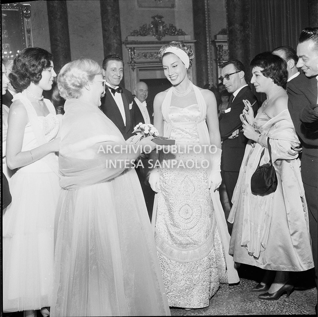 Jole Veneziani offre un dono a una spettatrice al Teatro alla Scala in occasione della serata inaugurale della stagione lirica 1957-1958 con l'opera "Un ballo in maschera", di Giuseppe Verdi, diretta da Gianandrea Gavazzeni e la regia di Margherita Wallmann