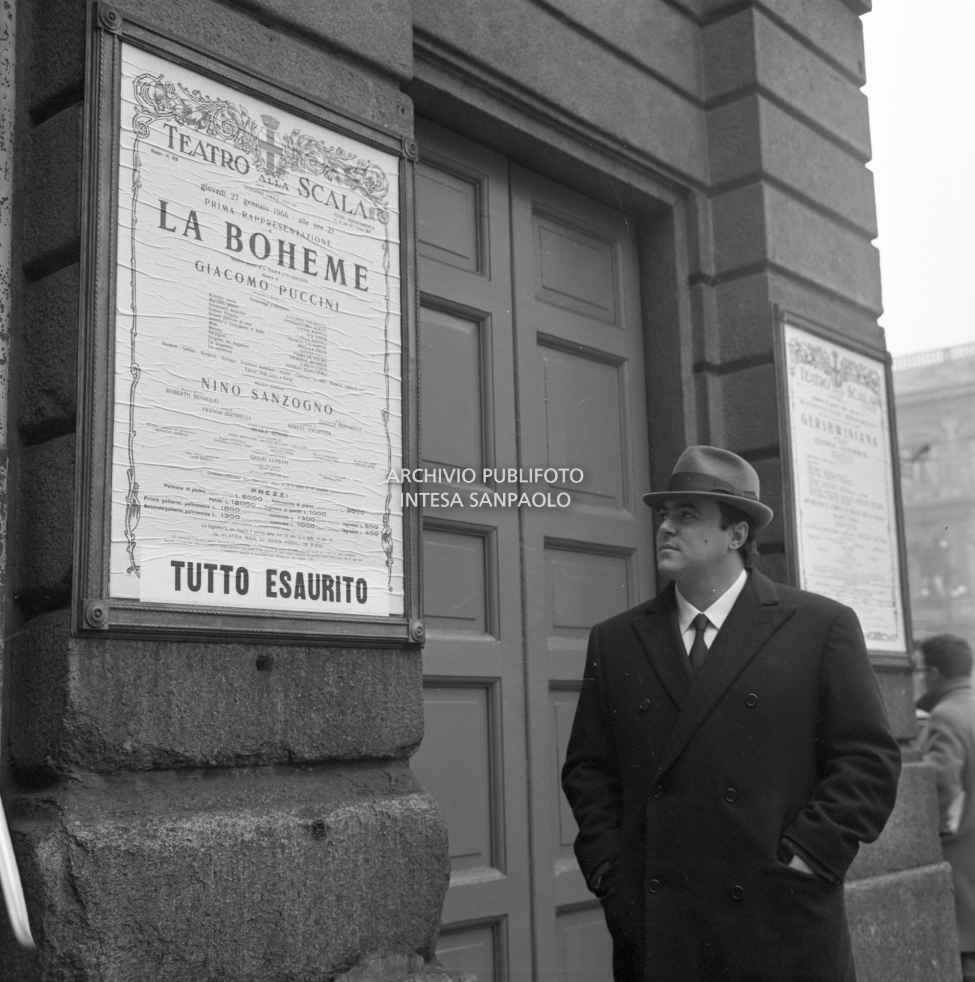 Luciano Pavarotti, ritratto a Milano a fianco al Teatro alla Scala, guarda il cartellone de La Bohème nella quale interpreta Rodolfo