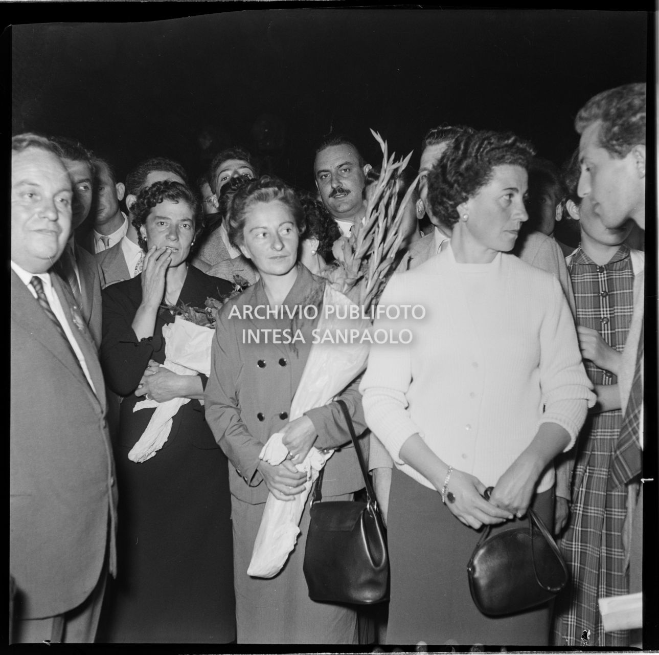 La moglie di Ubaldo Rey e quella di Achille Compagnoni tra la folla in attesa degli alpinisti di ritorno dalla spedizione sul K2 all'aeroporto Linate a Milano