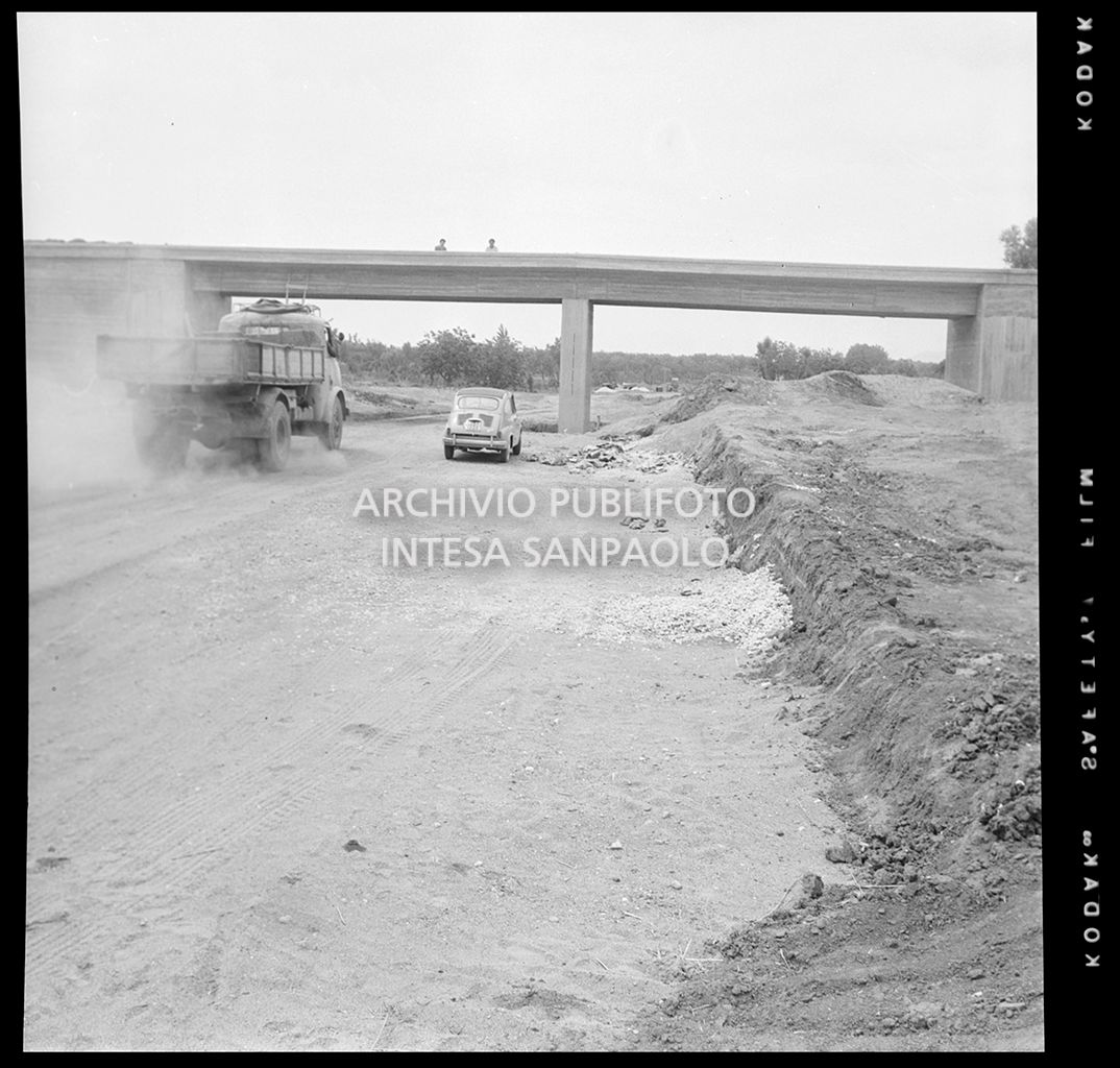 Un autocarro e un'automobile nel cantiere di costruzione dell'Autostrada del Sole, tratta Napoli-Capua