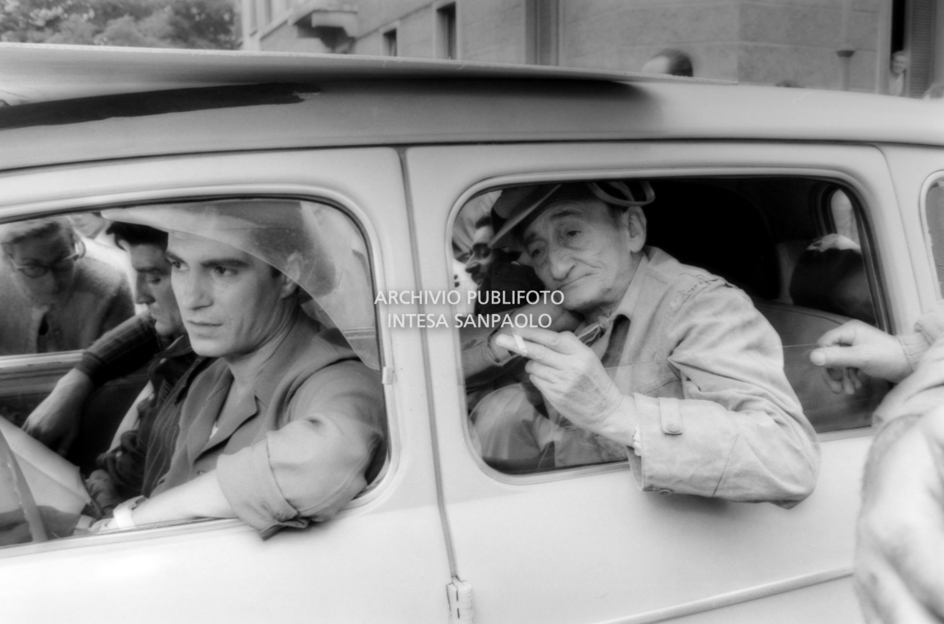 Riprese del film "Audace colpo dei soliti ignoti" a Milano; a bordo dell'automobile da sinistra in senso orario, Nino Manfredi, Vittorio Gassman e Carlo Pisacane