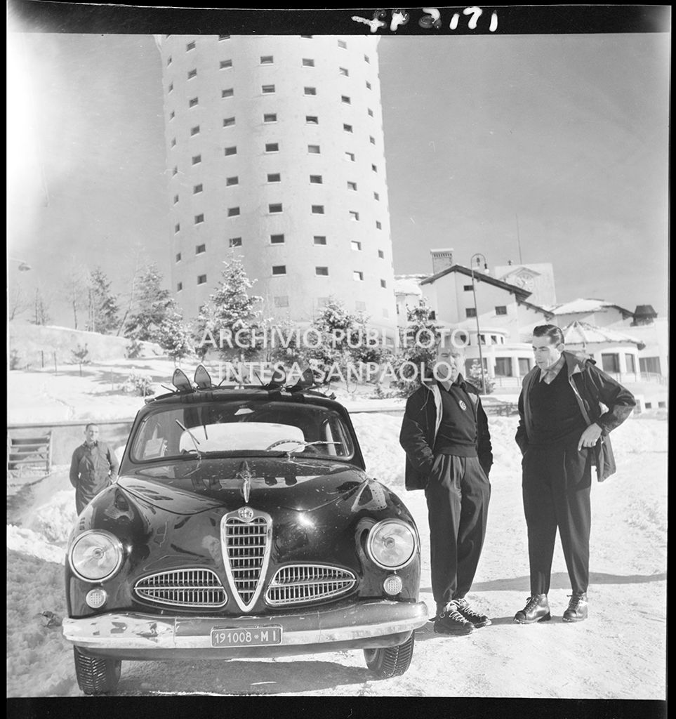 Giuseppe "Nino" Farina e Fausto Coppi a fianco a un'Alfa Romeo 1900; alla loro spalle l'Hotel La Torre al Sestriere
