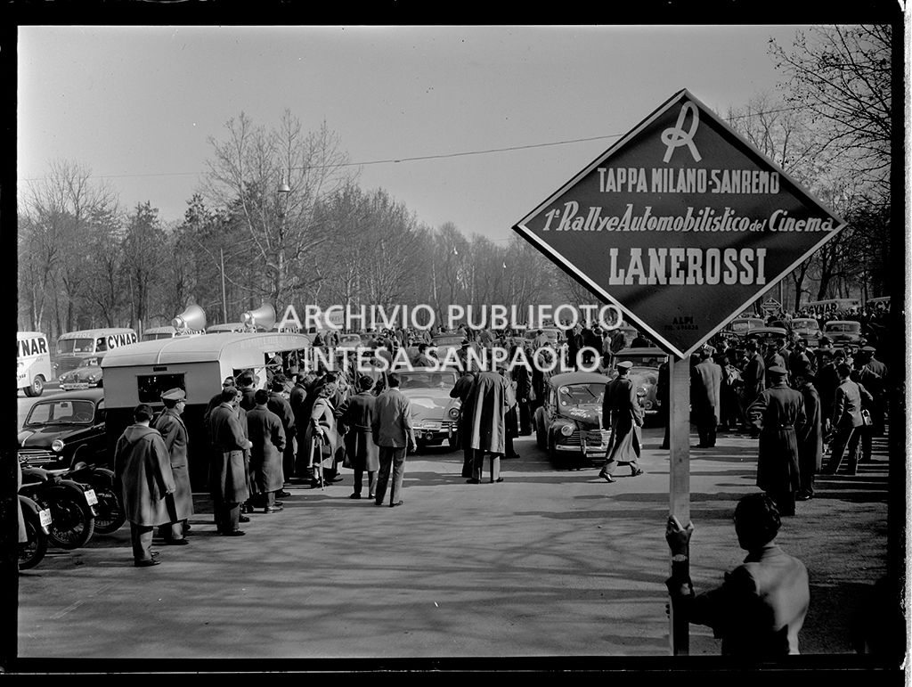 Partenza della tappa Milano-Sanremo del 1° Rallye automobilistico del cinema promosso da Lanerossi; in primo piano il cartello della tappa