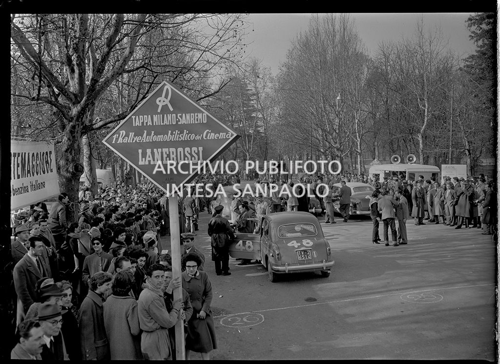 Partenza della tappa Milano-Sanremo del 1° Rallye automobilistico del cinema promosso da Lanerossi; in primo piano il cartello della tappa