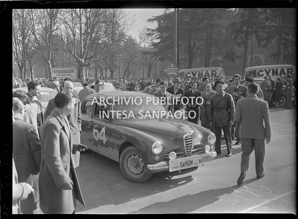 1° Rallye automobilistico del cinema per le vie di Milano: tappa Milano-Sanremo; in primo piano l'Alfa Romeo 1900 con cui gareggiano Yvonne Sanson e Paolo Marzotto ripreso nell'atto di salire in auto