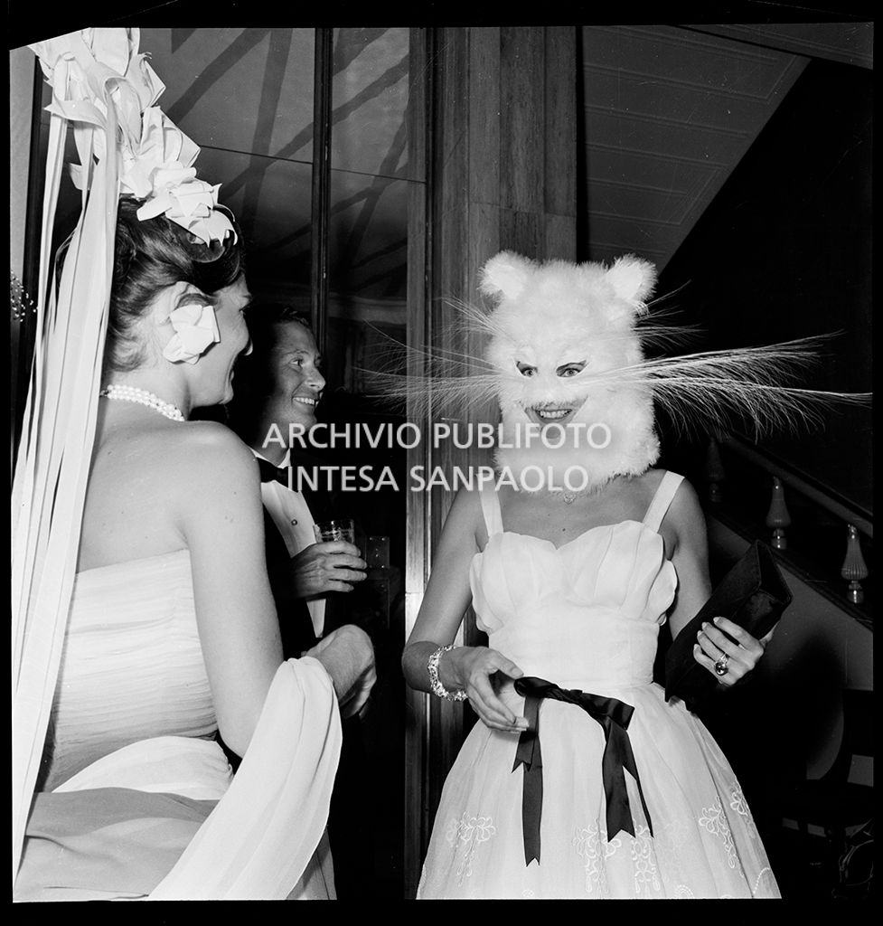 Domitilla Ruspoli, con la maschera da gatto, in compagnia del conte Brandolini e di Madame Patricia Lopez-Willshaw al ricevimento organizzato da Elsa Maxwell in onore di Maria Callas