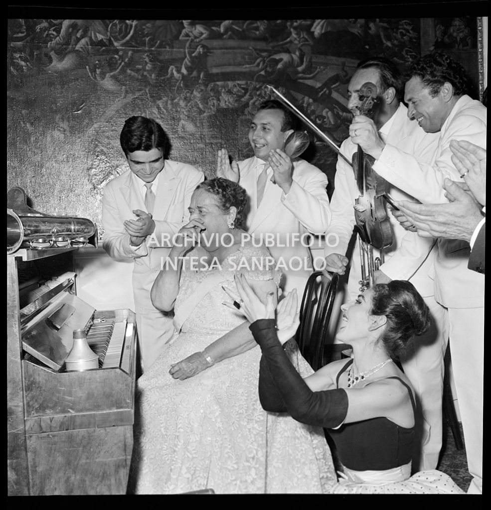 Elsa Maxwell applaudita dai musicisti e da Maria Callas per la sua esibizione al pianoforte al ricevimento in onore della soprano