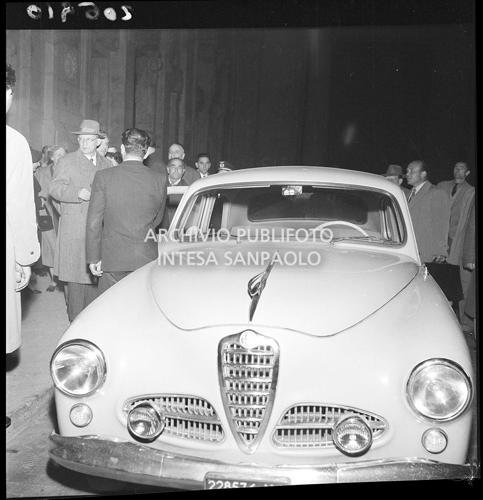 Alcide De Gasperi al suo arrivo alla Stazione Centrale di Milano; in primo piano un'Alfa Romeo 1900