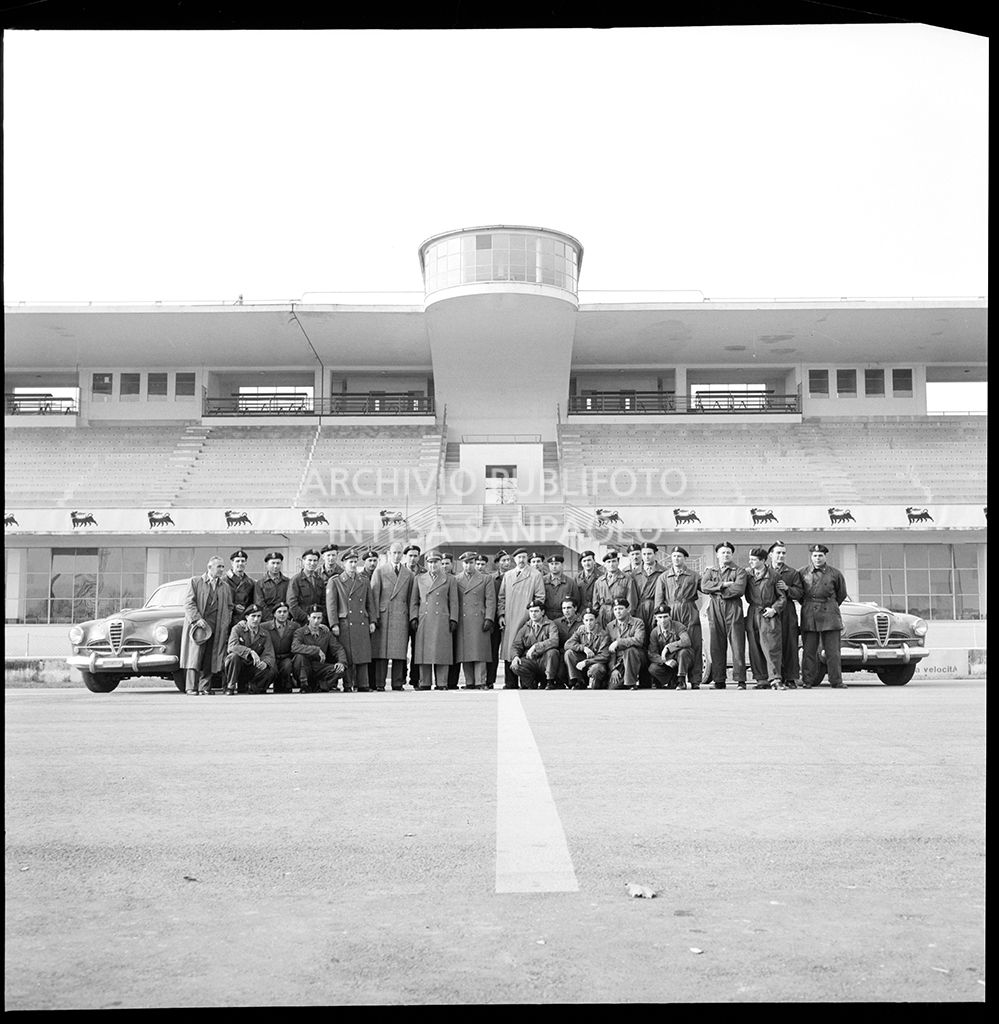 Foto di gruppo di uomini della Guardia di Finanza all'autodromo di Monza; ai lati Alfa Romeo 1900 Super/1900 TI Super